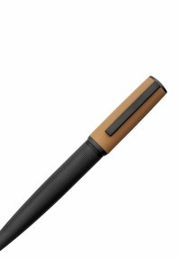 Črn pisalni instrument z teksturiranim oprijemom, ki ima rjav gumijast vrh in črn kovinski sponko. Spretna, podolgovata oblika.