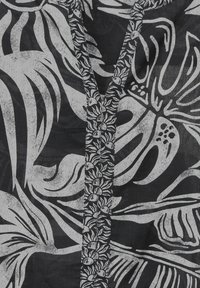 Tessuto nero con motivi floreali e foglie bianchi. Presenta un collo a V e dettagli testurizzati lungo la pattina.