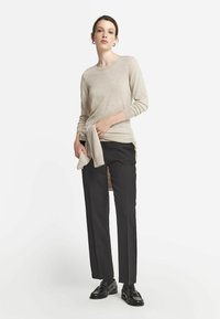 Ljusbeige långärmad tröja med en avslappnad passform, i kombination med skräddarsydda svarta byxor. Inkluderar rullad tygdetalj vid midjan.