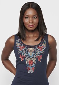 Marineblaues Tanktop mit aufwendiger floraler Stickerei in Rot, Blau und Creme, mit einem runden Ausschnitt und schmalen Trägern.