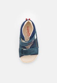 Blue toddler sandal with two adjustable Velcro straps, open toe, cushioned insole, and red, white, and blue fabric loop at heel.