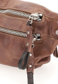 Bolso de cuero marrón con cremalleras metálicas, superficie texturizada y una correa de cuero negra con detalles de herrajes plateados.