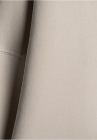 Světlý béžový látkový materiál se hladkou texturou a viditelným žebrovaným pleteným vzorem. Jemný lesk s čistým šitím podél okrajů.