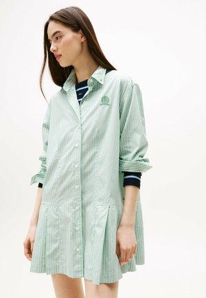 Abito camicia verde a righe con bottoni davanti, colletto a punta e pieghe nella gonna. Presenta un logo ricamato e maniche arrotolate.