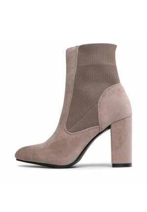 Fioletowy zamszowy botek za kostkę z dzianinową boczną wstawką i blokowym obcasem, z charakterystycznym spiczastym noskiem i gładką podeszwą.