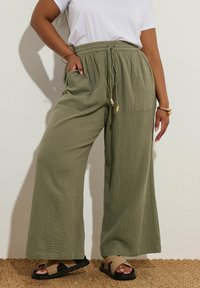 Keve, oliivivärvi laiad püksid tekstureeritud kangast, reguleeritava nöörivöökohtaga, küljetaskudega ja laia lõikega.