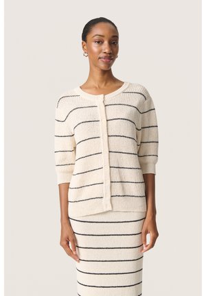 Creme cardigan med sorte striber, rund halsudskæring, knaplukning, trekvartærmer, ribbet tekstur. Kombination med en matchende stribet nederdel.