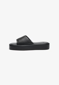 Black woven slide sandal with a thick platform sole and textured strap. Smooth footbed with a minimalist design.
