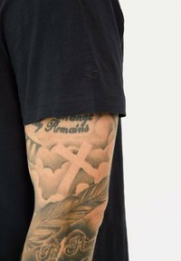Sort kortærmet T-shirt lavet af letvægtsstof med en subtil tekstur. Har et lille logo på ærmet og en tætsiddende pasform.