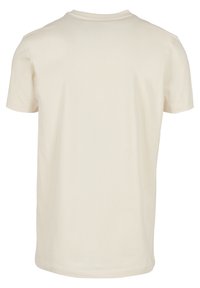 T-shirt crème uni à manches courtes vu de dos avec un col rond et un design simple.