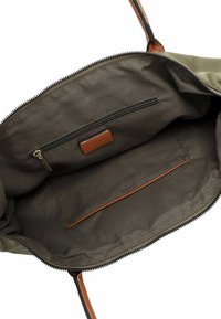 Borsa tote in tela verde oliva con chiusura a zip, caratterizzata da un accento in pelle marrone chiaro all'interno e una tasca laterale con zip per l'organizzazione.