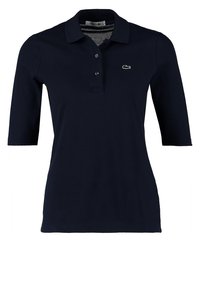 Marinpolo med kort ärm. Tillverkad av bomull, med en knappslå med tre knappar och broderad logotyp på bröstet. Slät textur.