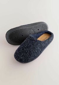 Navy blue fuzzy slippers with a textured upper, slip-on design, and a black molded rubber sole featuring a wavy pattern for grip.