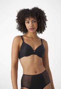 Schwarzer BH mit glatten Cups und strukturiertem Mesh-Bund. Verstellbare Träger. Hochgeschnittene schwarze Slips mit Diamantmuster und durchsichtigen Akzenten.