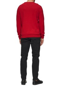 Rode crewneck trui van breiwerk, met lange mouwen, geribbelde zomen en een gladde textuur, gecombineerd met zwarte slim-fit jeans.