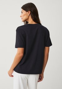 Zwarte katoenen t-shirt met een ronde halslijn, korte mouwen en een rechte zoom. Minimalistisch ontwerp zonder zichtbare patronen of accenten.