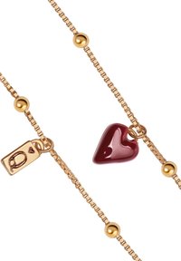 Złota naszyjnik łańcuchowy z czerwonym wisiorkiem w kształcie serca, okrągłymi złotymi koralikami oraz złotą zawieszką z wytłoczonym herbem.