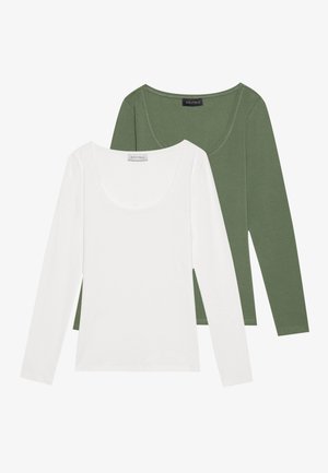 Deux chemises à manches longues, en blanc et en vert olive. Les deux ont un décolleté bateau. La chemise blanche est unie, tandis que la verte a une texture côtelée.