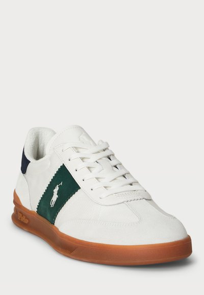 Λευκό αθλητικό παπούτσι με πράσινες και ναυτικές λεπτομέρειες, κατασκευασμένο από σουέτ και καμβά, με επίπεδα κορδόνια και καουτσούκ σόλα που φέρει το λογότυπο "Polo".