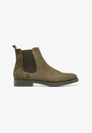 Bottines Chelsea en suède vert olive avec des panneaux latéraux élastiques et une languette, dotées d'un bout arrondi et d'un petit talon empilé.