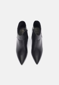 Bottines en cuir noir à bout pointu, texture lisse et détail de fermeture éclair latérale. Pas de motifs ni d'accents visibles.