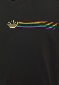 Schwarzes T-Shirt mit einem goldenen Logo und mehrfarbigen horizontalen Streifen in Rot, Orange, Gelb, Grün, Blau und Lila. Weicher Stoff.