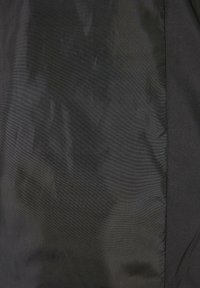 Čierny textil s hladkou textúrou, s jemným leskom a variabilitou odtieňov. Obsahuje minimálne švy a má celkový plochý dizajn.