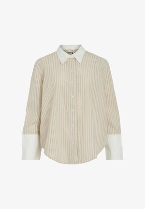 Šviesiai smėlio spalvos marškiniai su plonomis dryžiais, balta apykakle ir rankovėmis. Turi mygtukų uždarymą priekyje ir išlinkusį kraštą, pagaminti iš minkštos medžiagos.