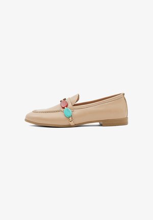 Beige leren loafer met lage hak, met decoratieve rode en turquoise ovale accenten op de band bovenop.