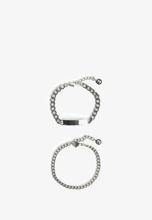 Két ezüstszínű lánc karkötő: az egyik egy lapos, fényes rúddal, a másik pedig egy egyszerű lánc dizájnnal és egy kis medállal rendelkezik.