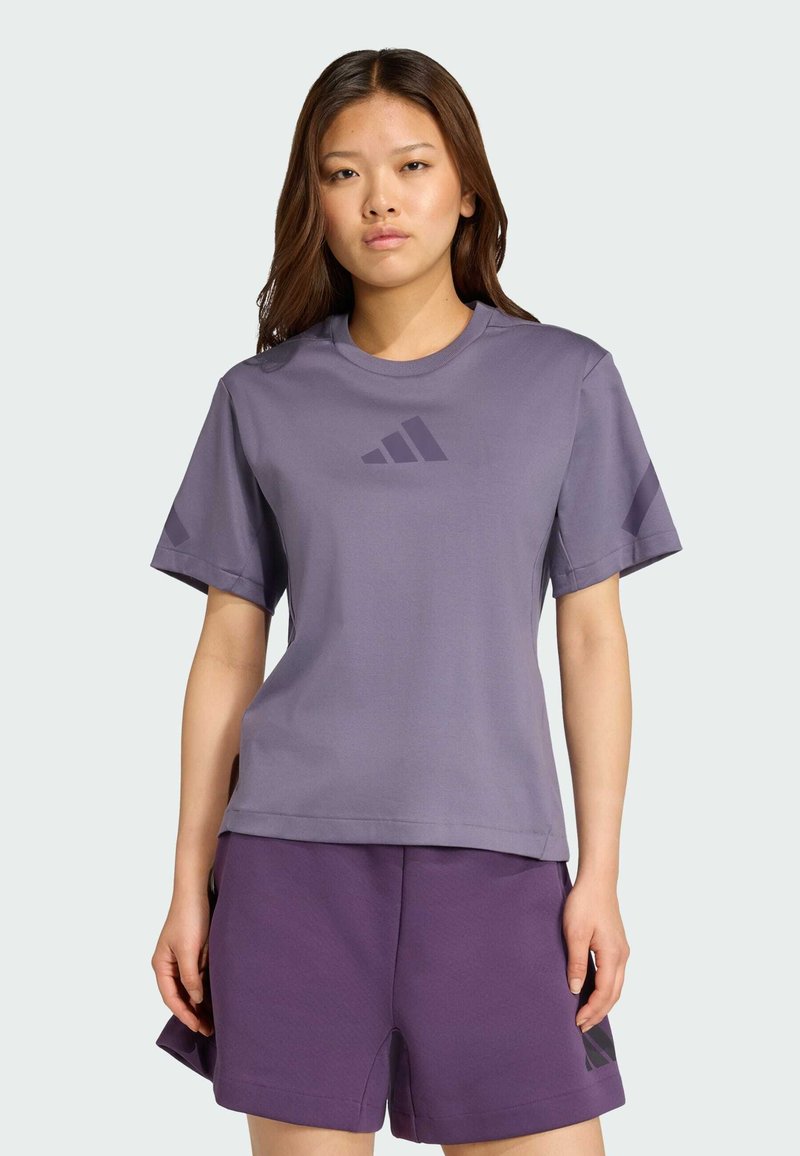 Lila tränings-T-shirt med kort ärm, slätt tyg, rund halsringning, med en mörkare lila logotyp på framsidan och matchande lila shorts.