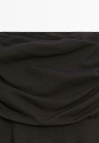 Schwarzer gerippter Strickstoff mit sichtbaren Falten und Struktur, wahrscheinlich Teil eines Kleidungsstücks oder Textilmaterials.