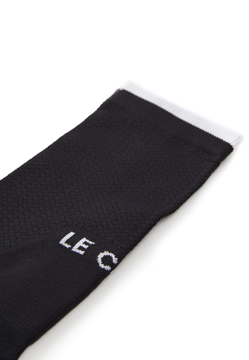 Czarne skarpetki z teksturowanym wzorem, z białym ściągaczem i nadrukowanym białym tekstem "LE C." Wykonane z miękkiego, oddychającego materiału.