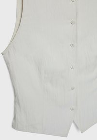 Sleeveless, off-white vest top featuring a subtle texture, front button closure, and side pockets; straight hem with a slight curve.