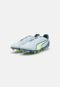 Scarpini da calcio di colore blu chiaro con accenti gialli e navy, tomaia sintetica, superficie testurizzata e tacchetti verdi per aderenza sull'erba.