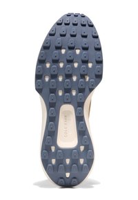 Sole sportovní obuvi s tmavě modrým gumovým povrchem, který má vyvýšené trojúhelníkové protiskluzové vzory a světlý mezipodešev s logem.