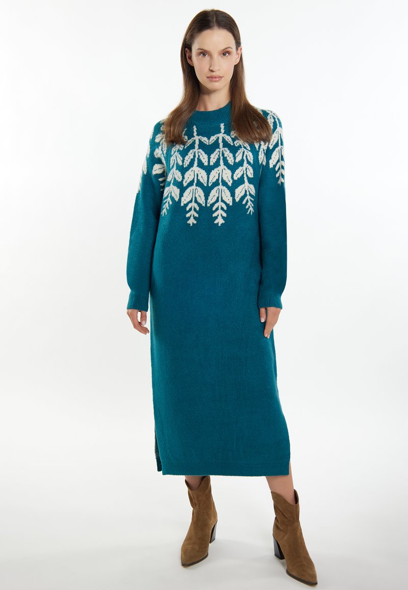 Türkis gestricktes Kleid mit einem weißen Blattmuster, langen Ärmeln, Rundhalsausschnitt, seitlichen Schlitzen und geradem Schnitt.