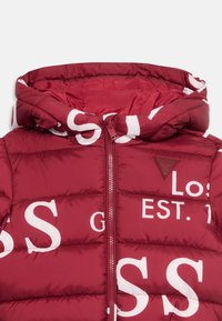 Red puffer jacket with large white lettering. Features a hood, zippered front, and a logo badge. Padded texture with quilted sections.