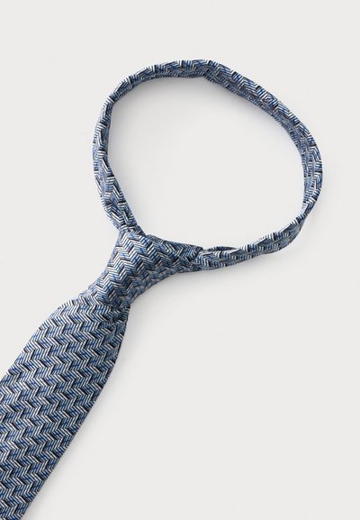 Cravate en soie à motifs bleus et blancs avec un nœud pré-noué formant une boucle sur un fond clair uni.