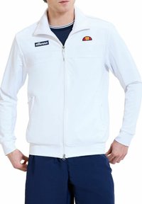 Witte zip-up jas van glad materiaal, met een staande kraag, zwart logo en een meerkleurig logoontwerp op de borst.