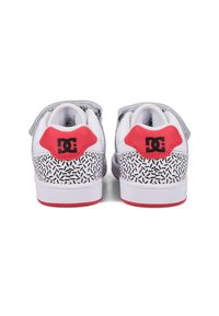 Białe sneakersy z teksturowaną, czarno-białą wzorzystą podeszwą pośrednią, czerwonymi akcentami na pięcie oraz szarym paskiem na górze.