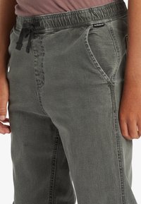 Pantalones joggers de mezclilla gris con cintura elástica, cordón ajustable, bolsillos laterales y un acabado suave y texturizado.