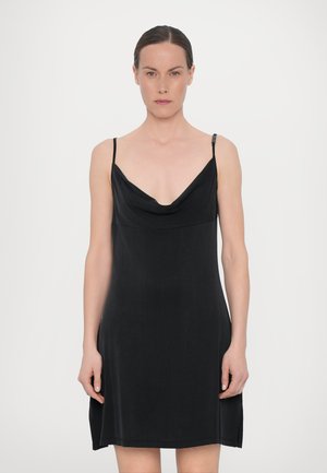 Robe noire sans manches avec bretelles spaghetti, décolleté en cowl, texture lisse et ourlet qui tombe au-dessus des genoux, avec de subtils fentes latérales.