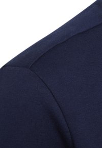 Tejido de suéter azul marino con una textura suave. Primer plano que muestra la costura del hombro y el patrón de punto. Material ligero, con un diseño ajustado.
