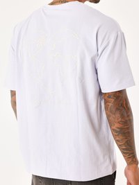 Camiseta de algodón lavanda clara con un contorno de globo en forma de corazón y el texto "Project x Paris" en dorado en la parte posterior. Mangas cortas.
