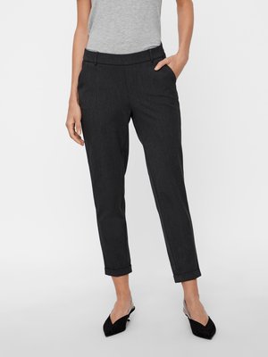 Pantaloni tailored grigio scuro con vestibilità affusolata, che creano una silhouette pulita. Presentano tasche frontali e orli arrotolati. Indossati con una maglia grigia e scarpe nere.