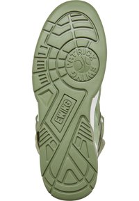 Suela de zapato de goma verde con patrón de agarre texturizado, que presenta un logotipo circular y el nombre de la marca "EWING" en relieve cerca del talón y la sección media del pie.