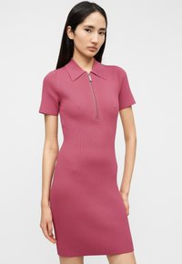 Ριμπ ροζ φόρεμα με κοντό φερμουάρ και γιακά. Εφαρμοστή γραμμή με κοντά μανίκια, που αναδεικνύει μια ομαλή υφή.