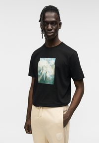 Μαύρο βαμβακερό t-shirt με μπλε και πράσινο γραφικό τύπωμα βουνών και δέντρων, λαιμόκοψη, κοντά μανίκια και άνετη εφαρμογή.