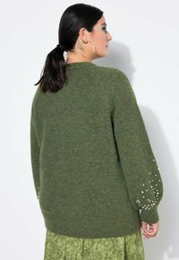 Pullover verde in maglia con maniche lunghe, caratterizzato da dettagli in perle sui polsi. Texture morbida, vestibilità morbida e dettaglio a costine sull'orlo.